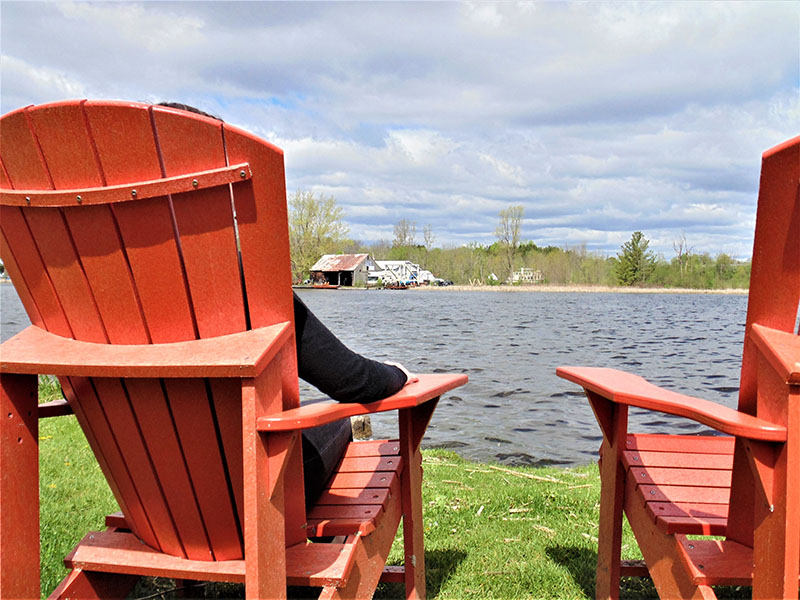 2 red deck chairs overlooking the rideau river.